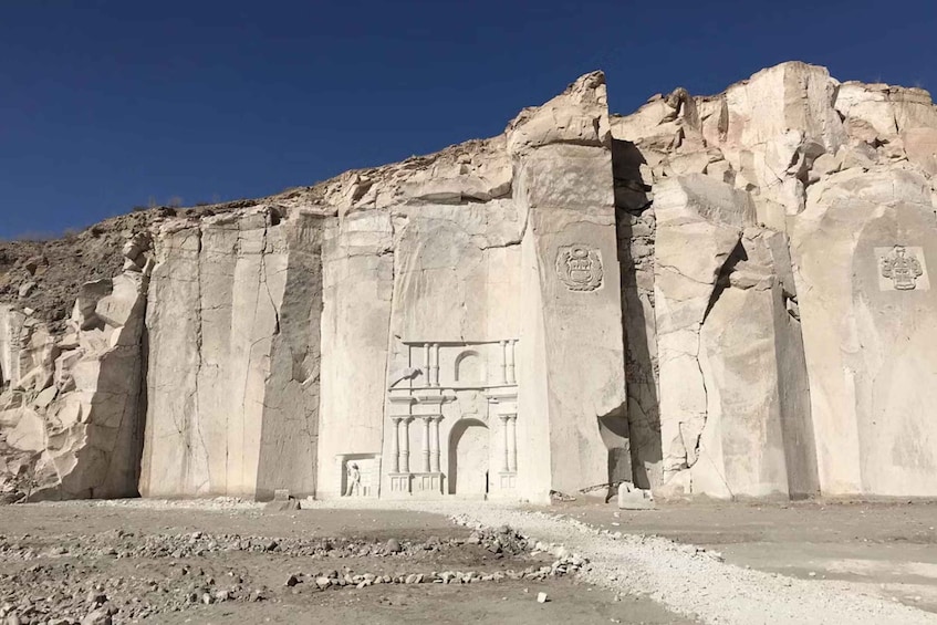 A large rock face with ancient carvings and inscriptions. 4