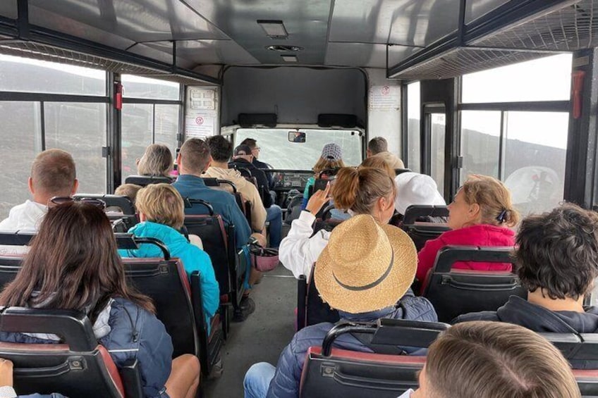 Passengers seated on a bus, looking out through large windows. 3