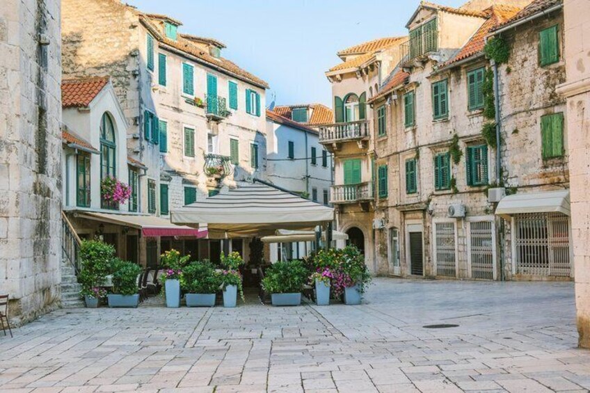 Un cortile in pietra con edifici, una zona salotto coperta e piante in vaso. 2