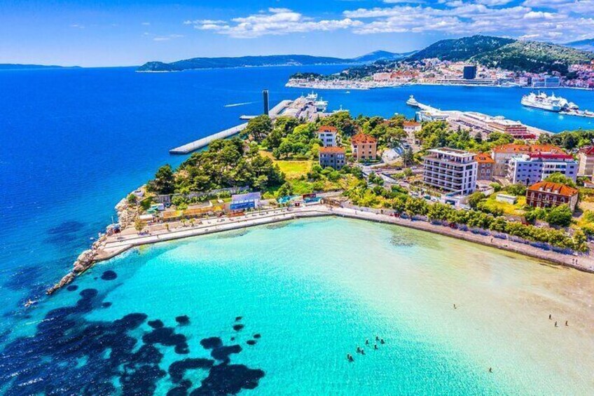 Una cittadina costiera con un mare cristallino, una spiaggia sabbiosa e un mix di edifici residenziali e commerciali. 3