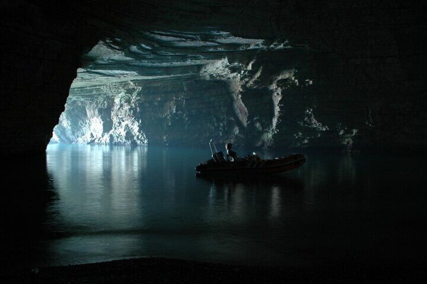 Un bateau dans une grotte, l’eau reflétant la lumière provenant de l’intérieur de la grotte. 2