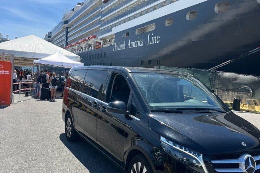 En sort Mercedes-Benz varevogn parkeret foran et Holland America Line krydstogtskib. 3
