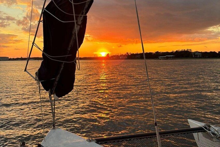 Un atardecer sobre una superficie acuática tranquila con un velero. 2