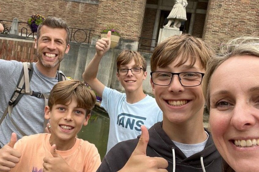 A group of people in front of a brick building with a statue. 4