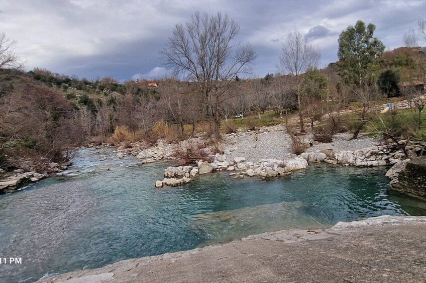 A river with clear water, surrounded by rocky terrain and sparse vegetation. 3
