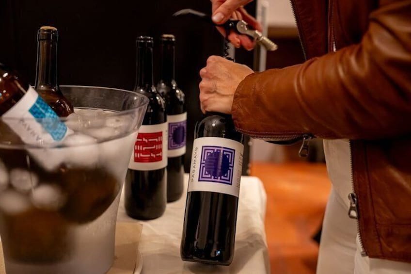 A person pouring wine into a glass from a bottle. 5