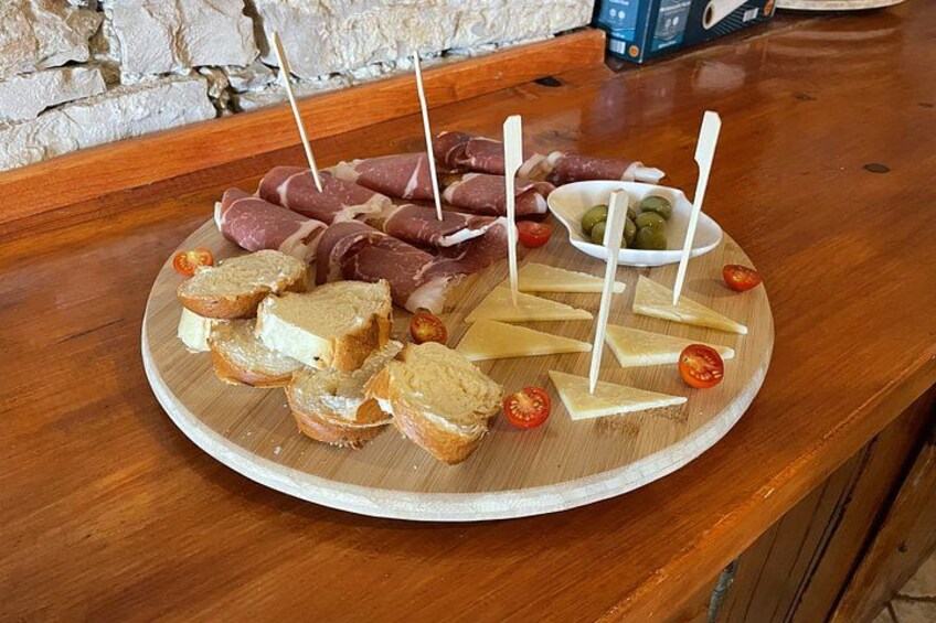 A wooden board with various meats, cheese, and bread on a table. 2