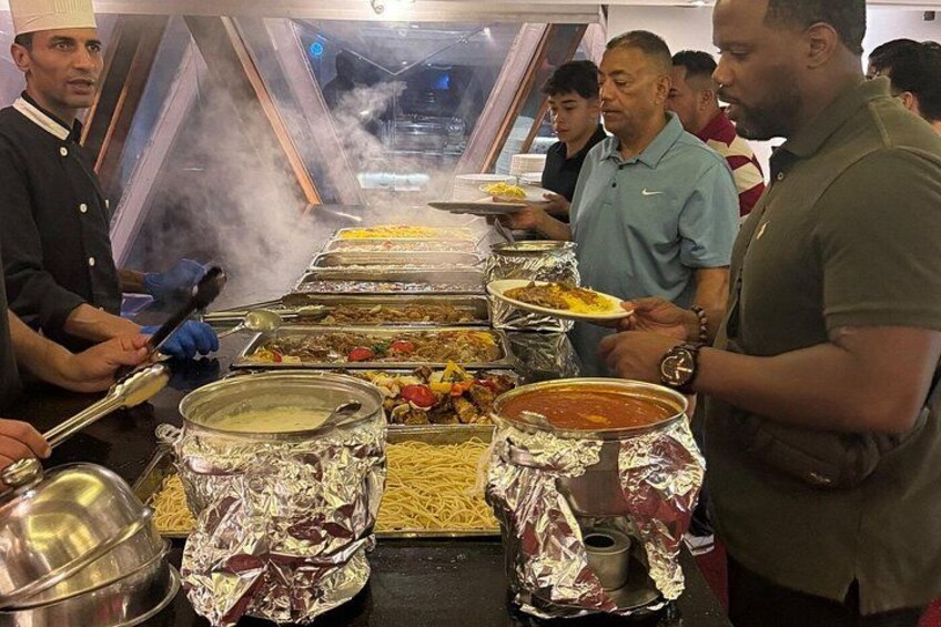 A buffet line with various dishes and a cook serving food. 3