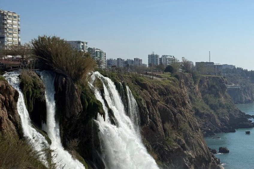 A waterfall cascading down a cliff with buildings in the background. 5