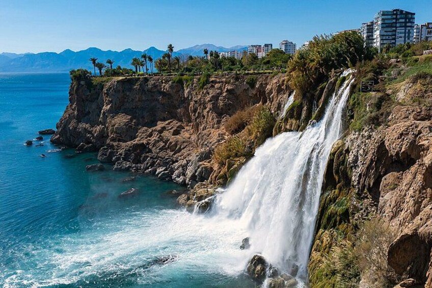 Een waterval aan de kust, met een helder uitzicht op de oceaan en bergen op de achtergrond. 5