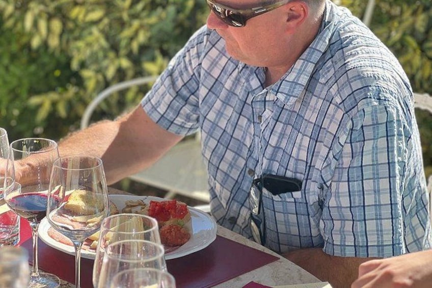 A person sitting at a table with a plate of food and wine glasses. 3