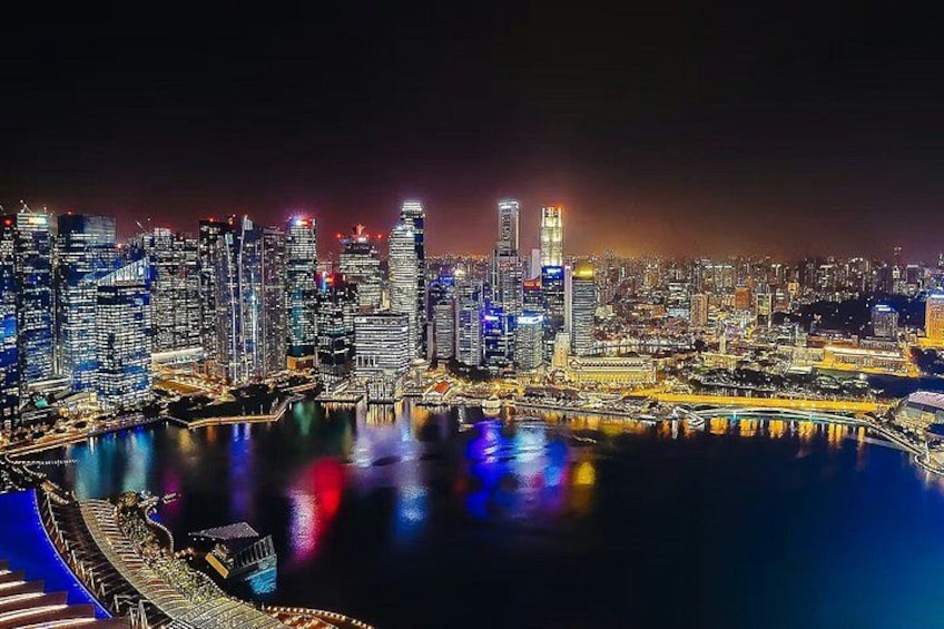 A nighttime cityscape with illuminated skyscrapers and a waterfront reflecting the lights. 4