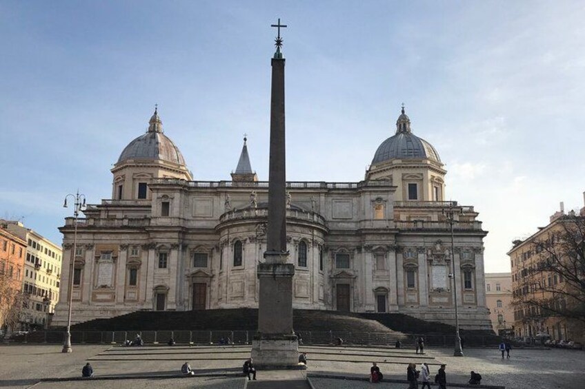 A large historical building with two domes and a tall obelisk in front. 1