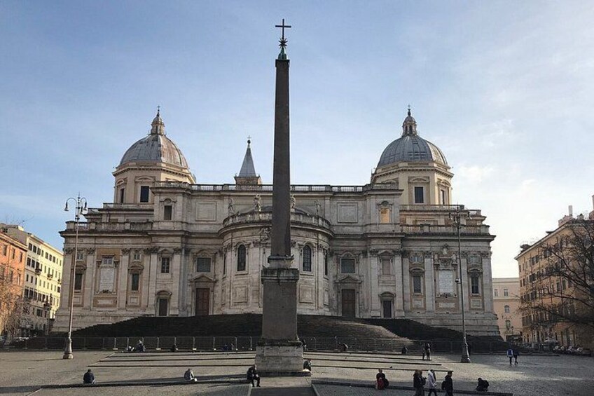 A large historical building with two domes and a tall obelisk in front. 1