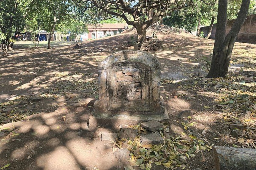 Ett väderbitet stenmonument omgivet av träd i en park. 2