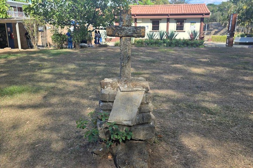 Ett monument av sten med en minnesplatta, omgivet av gräs och träd. 3