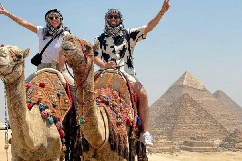 Due persone a dorso di cammelli, con una piramide sullo sfondo. 2