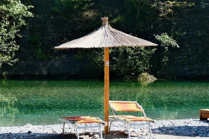 A beach with a thatched umbrella and two sun loungers. 3