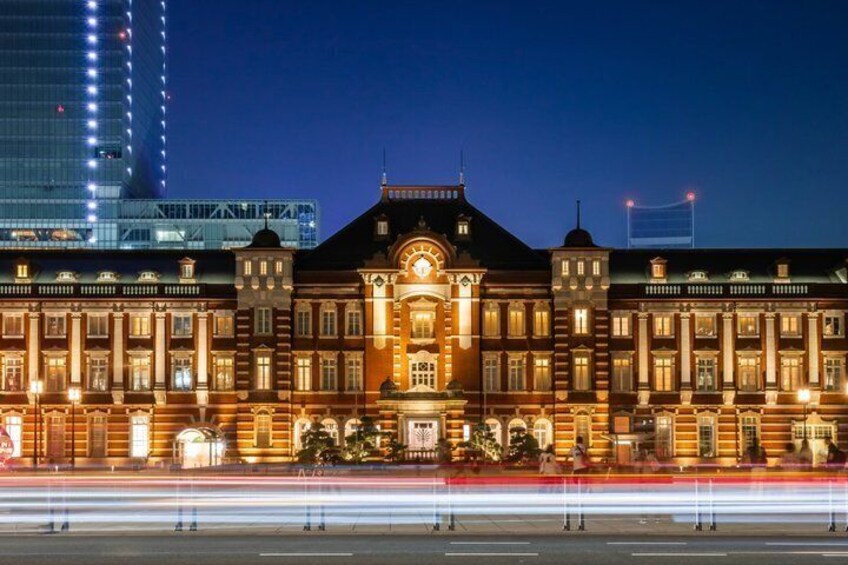 En storslået, oplyst bygning med klassisk arkitektur, en moderne skyskraber i baggrunden og en livlig gade med lyseffekter. 3