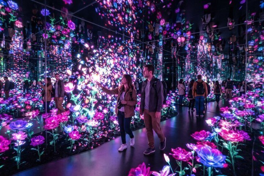 Een ruime binnenruimte vol kleurrijke, verlichte bloemen en mensen die er rondlopen. 3