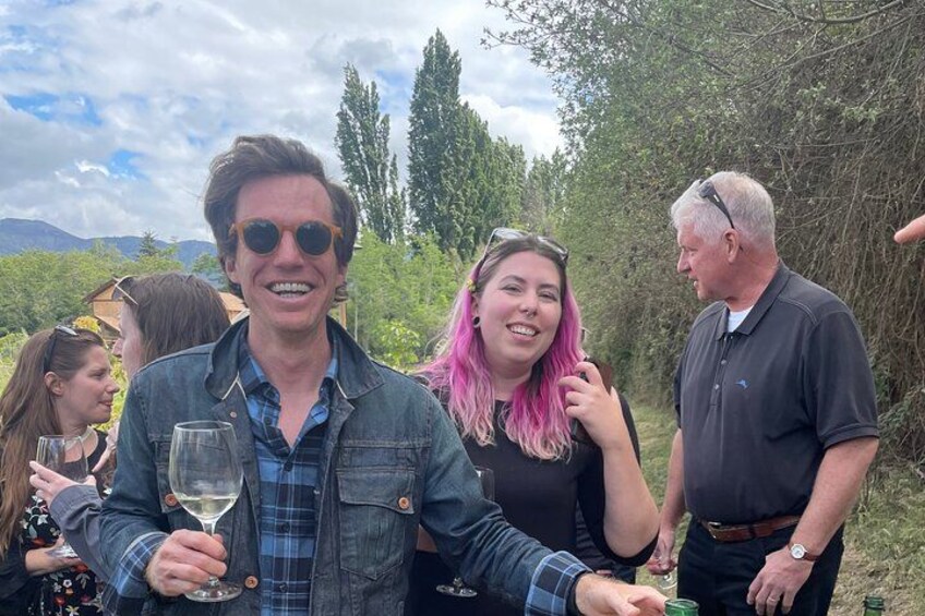 A group of people outdoors, some holding glasses, likely enjoying a drink. 2