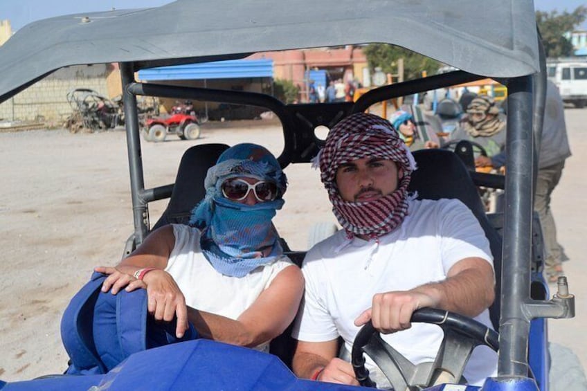 Two people in a vehicle with a blue cover, a man driving and a woman sitting beside him. 5