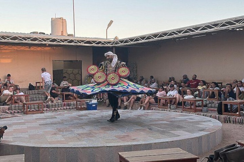 A person performing with a colorful umbrella in an outdoor setting with an audience. 3