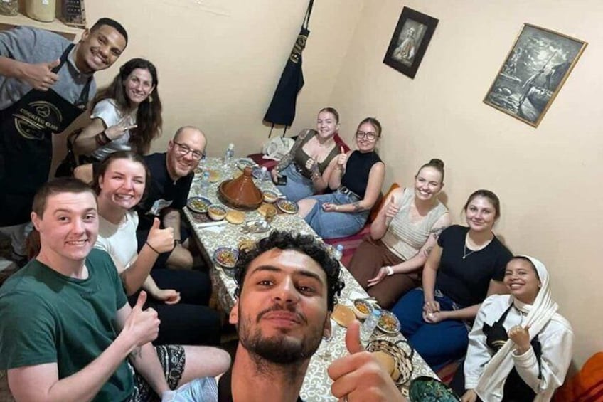 Un grupo de personas alrededor de una mesa con comida y bebidas, en una habitación con una bandera y cuadros en la pared. 1