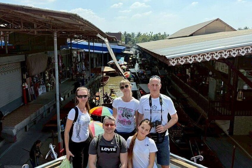 A group of people on a boat in a market area with stalls and a covered walkway. 3