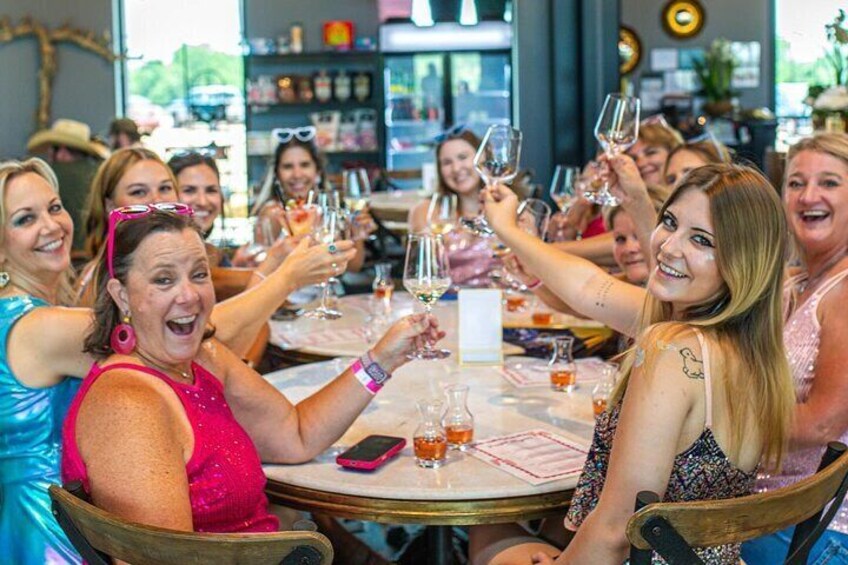 En gruppe mennesker skåler med vinglas ved et rundt bord i en restaurant. 2