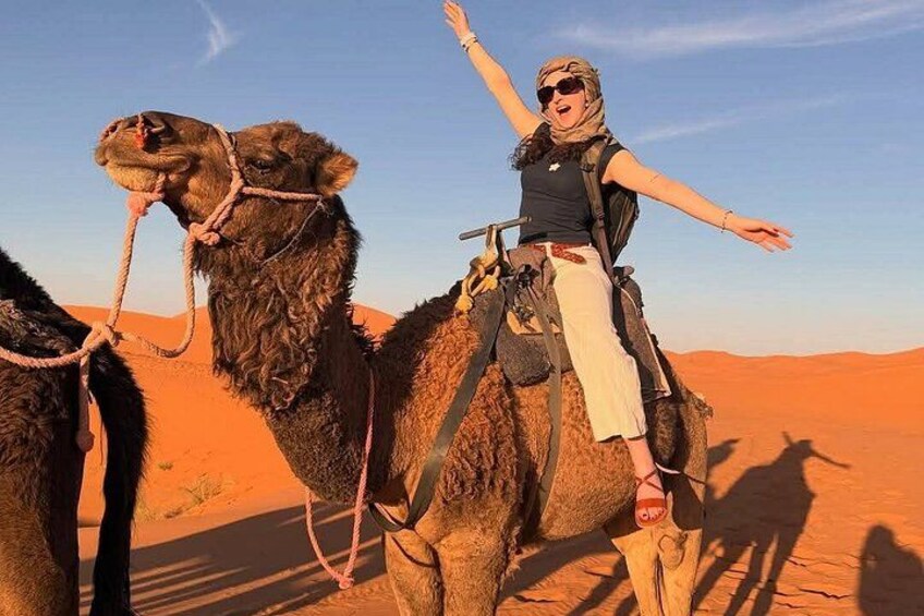 Eine Person reitet auf einem Kamel durch eine Wüstenlandschaft. 1