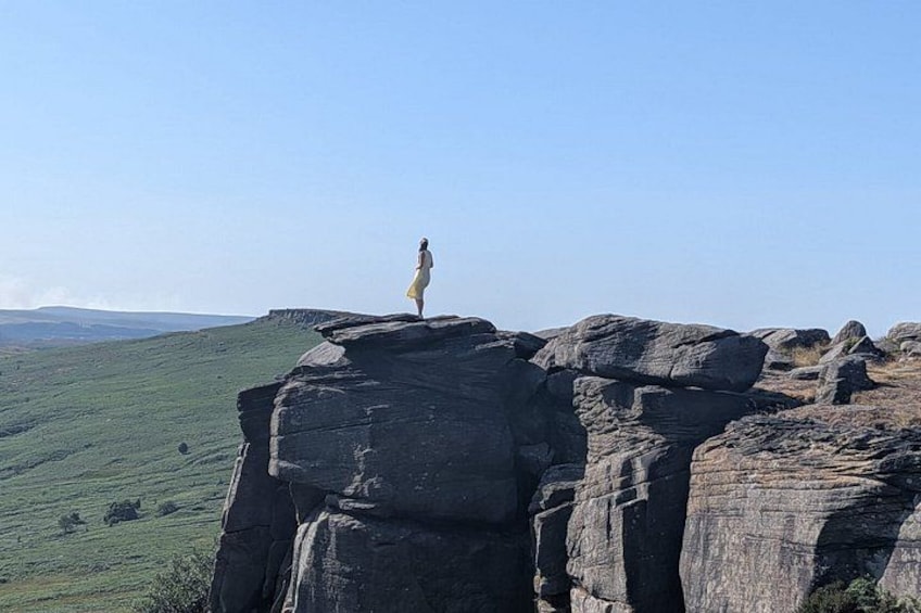 Eine Person steht auf einer Felsformation, im Hintergrund eine weite Landschaft. 3