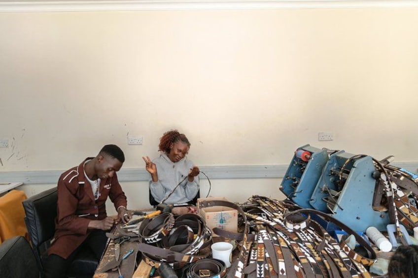 Two people working with electronic equipment on a table in a room with a plain wall. 4