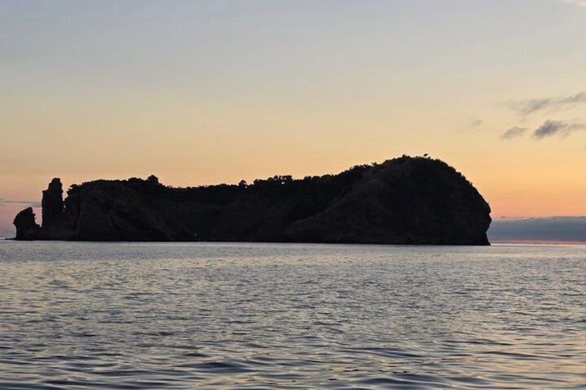 A large, isolated island with a rocky coastline at sunset. 3