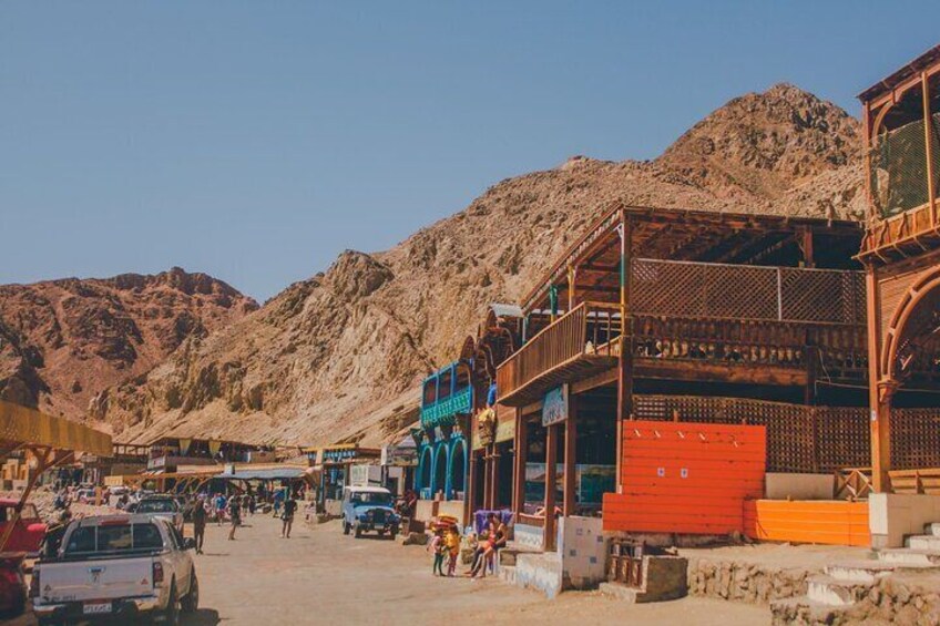A desert town with buildings, a mountain in the background, and people walking on the street. 2