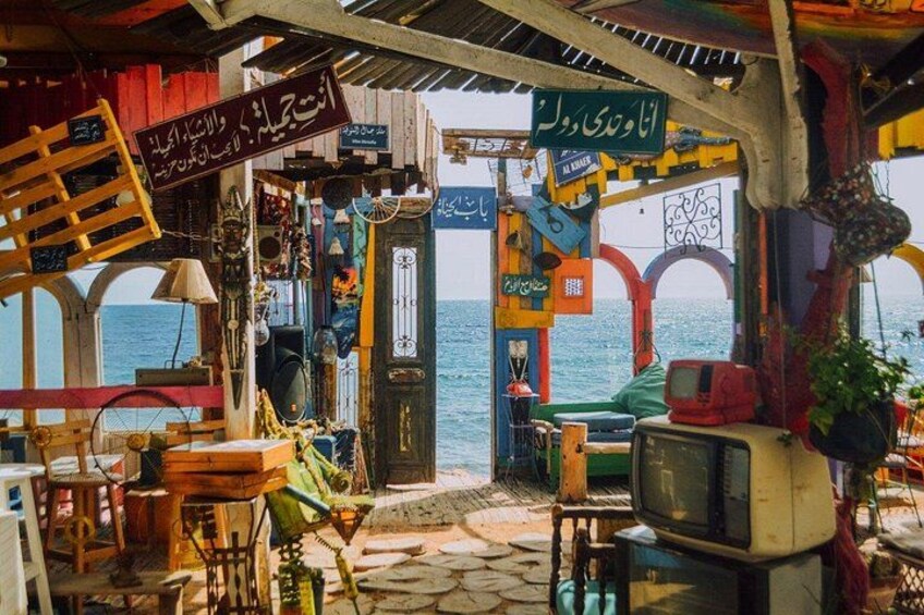 Ein bunter Markt im Freien mit verschiedenen Ständen und Blick auf das Meer. 4