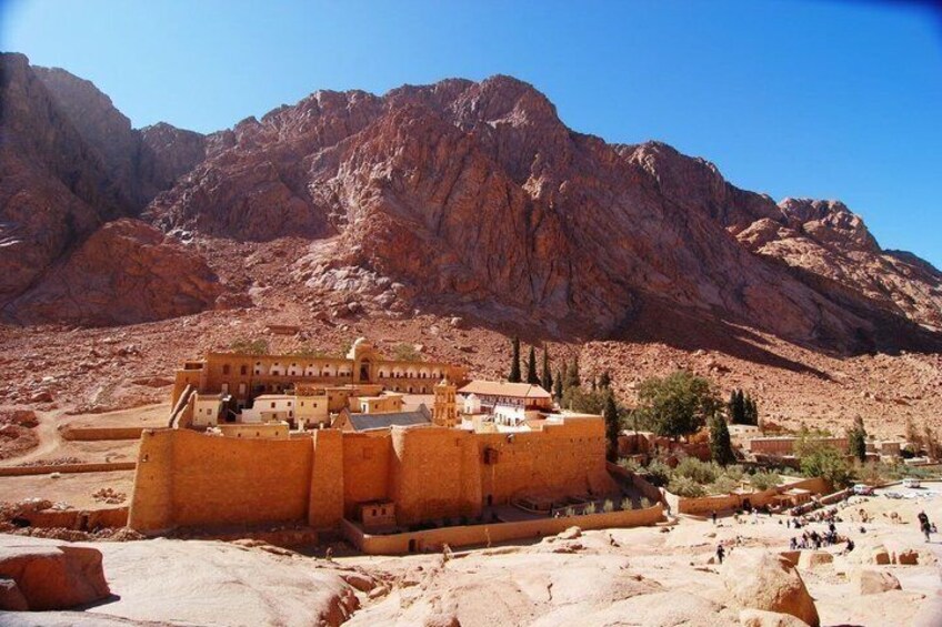 A desert landscape with a large, ancient walled structure in the foreground and mountains in the background. 1