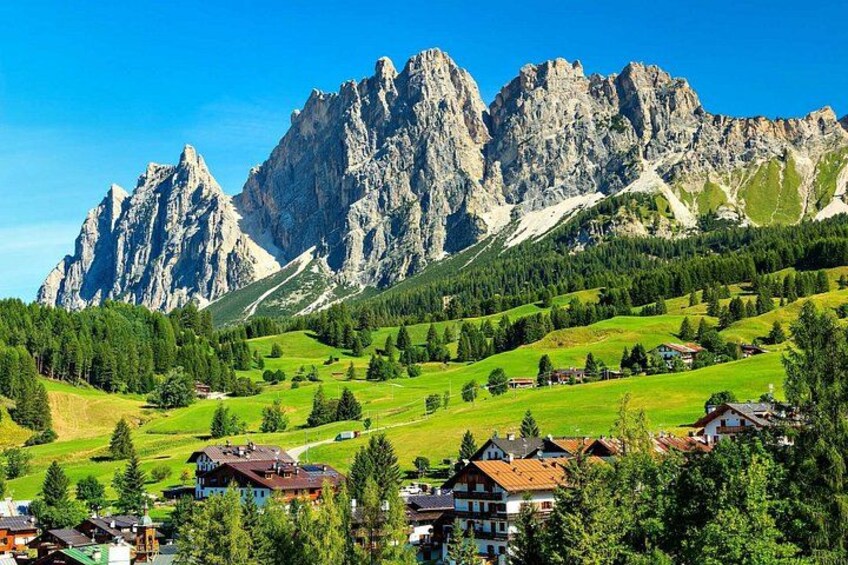 A mountainous landscape with houses and green fields. 2