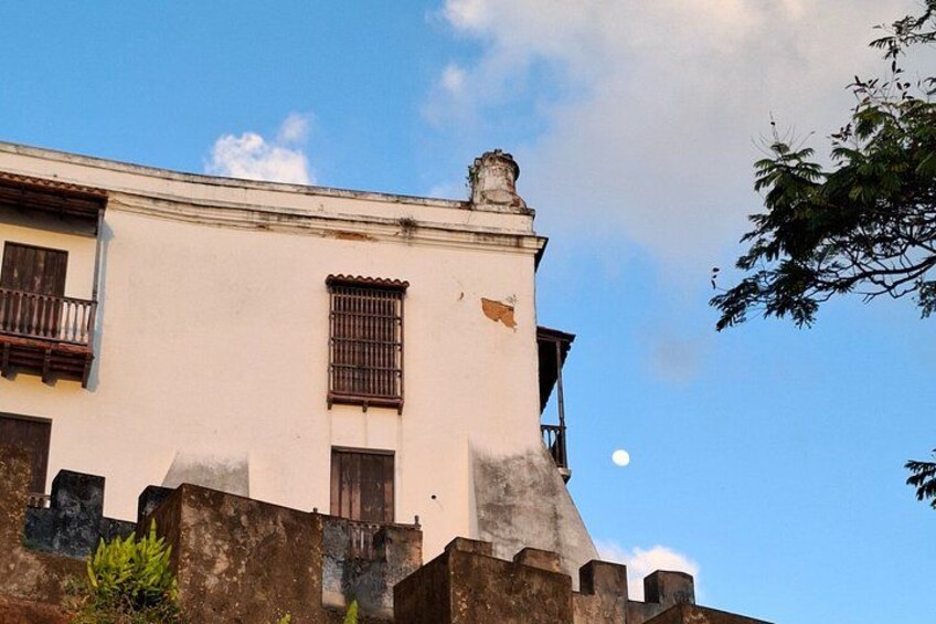 Ein weißes Gebäude mit einem Balkon, einem Fenster mit Gitter und einem Mond am Himmel. 5