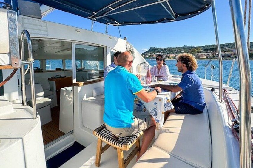 A boat with people seated at the stern, a clear sky, and a coastline in the background. 3