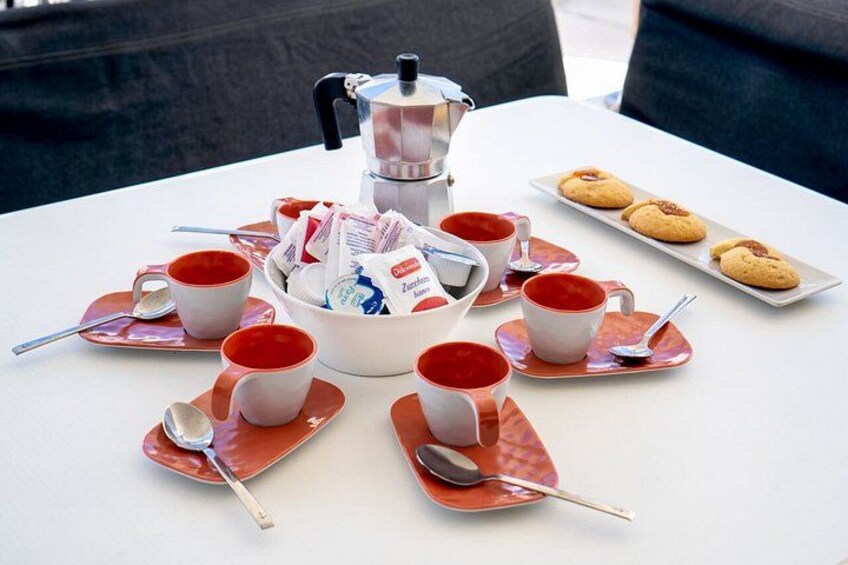 A table with a coffee pot, cups, saucers, and cookies. 2