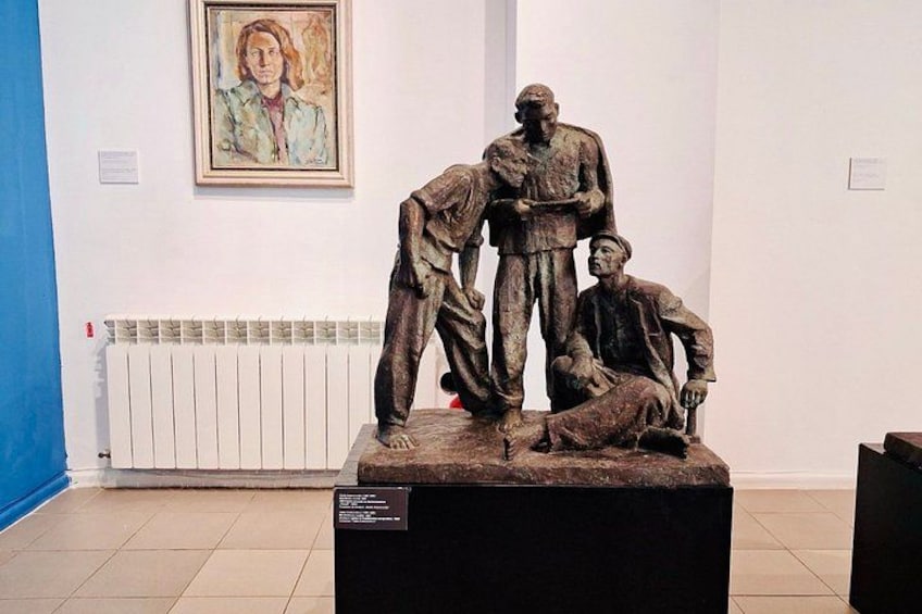 A sculpture of three figures in a museum setting. 2