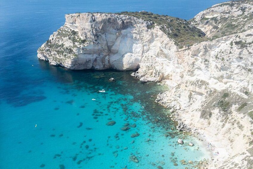 A coastal cliff with clear turquoise waters and rocky terrain. 2