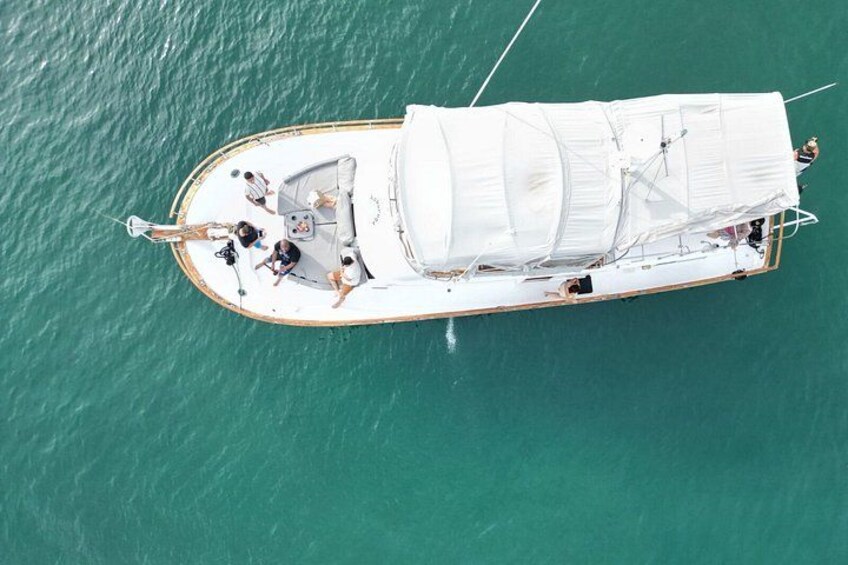 Eine Segelyacht mit weißem Segel und mehreren Passagieren. 2