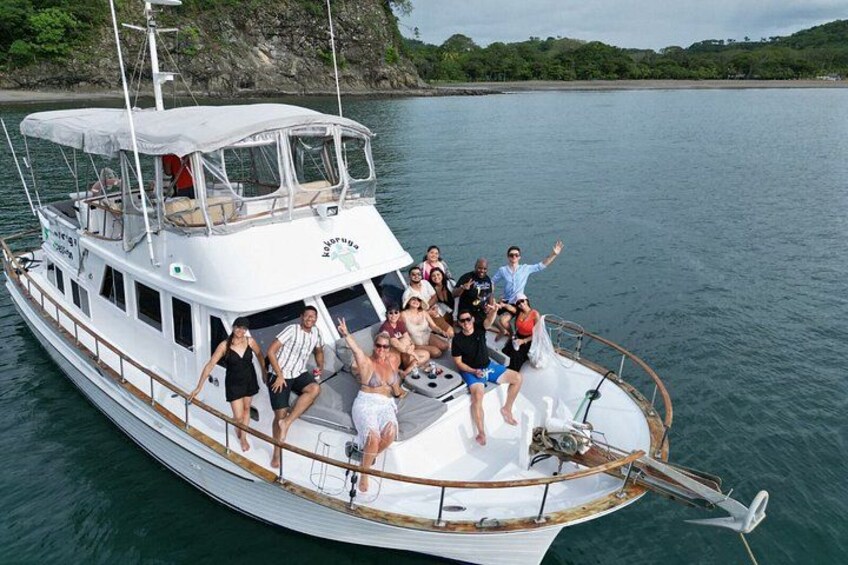 Ein weißes Boot mit Personen an Deck, umgeben von ruhigem Wasser und Grün in der Ferne. 1