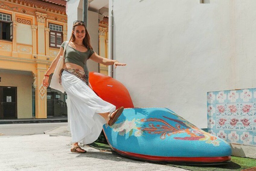 Una persona realizando un movimiento de baile sobre una esterilla de colores, con un edificio al fondo. 3