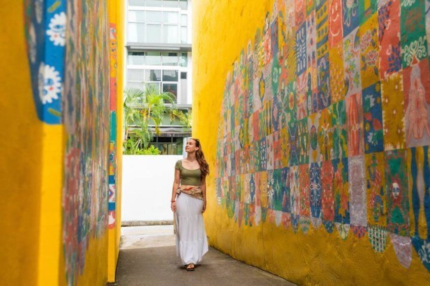 A person walking through a corridor with colorful murals on the walls. 4