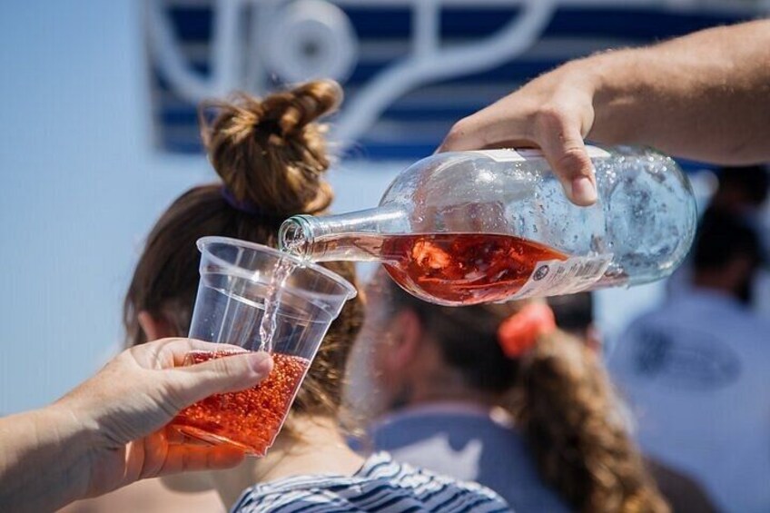 Eine Person gießt eine rote Flüssigkeit aus einer Flasche in einen durchsichtigen Plastikbecher. 2