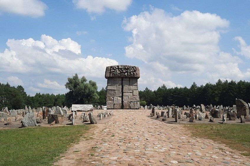 Een stenen monument met inscripties, omringd door tal van grafstenen in een begraafplaats. 3