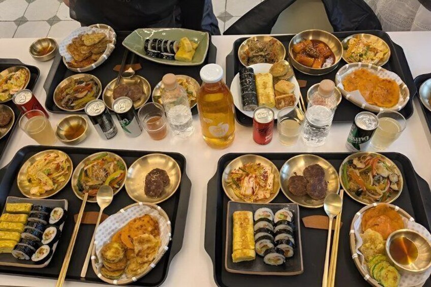 Una mesa con diversos platos, como sushi, sashimi y otras especialidades asiáticas, junto con bebidas y salsas. 3